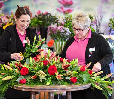 Photo of two florists around a table of flowers